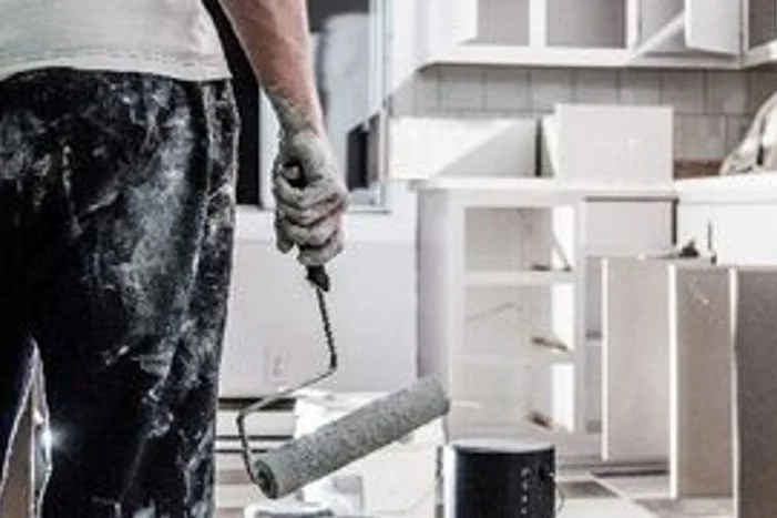 Person mit Farbrolle in renovierter Küche